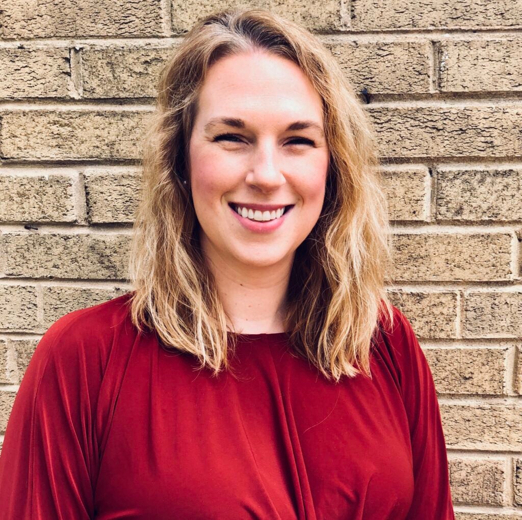 woman in front of brick wall smiling