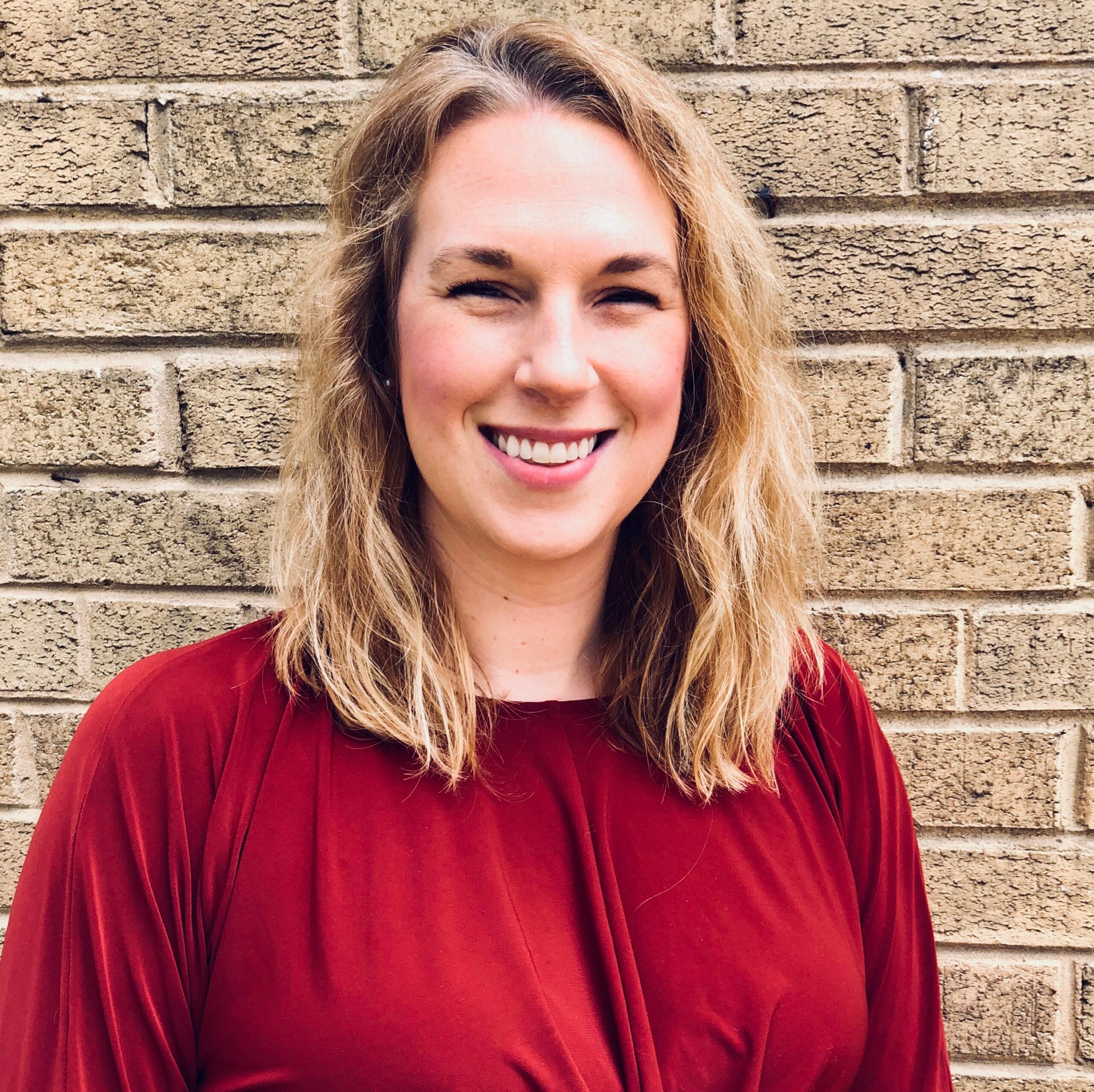 woman in front of brick wall smiling
